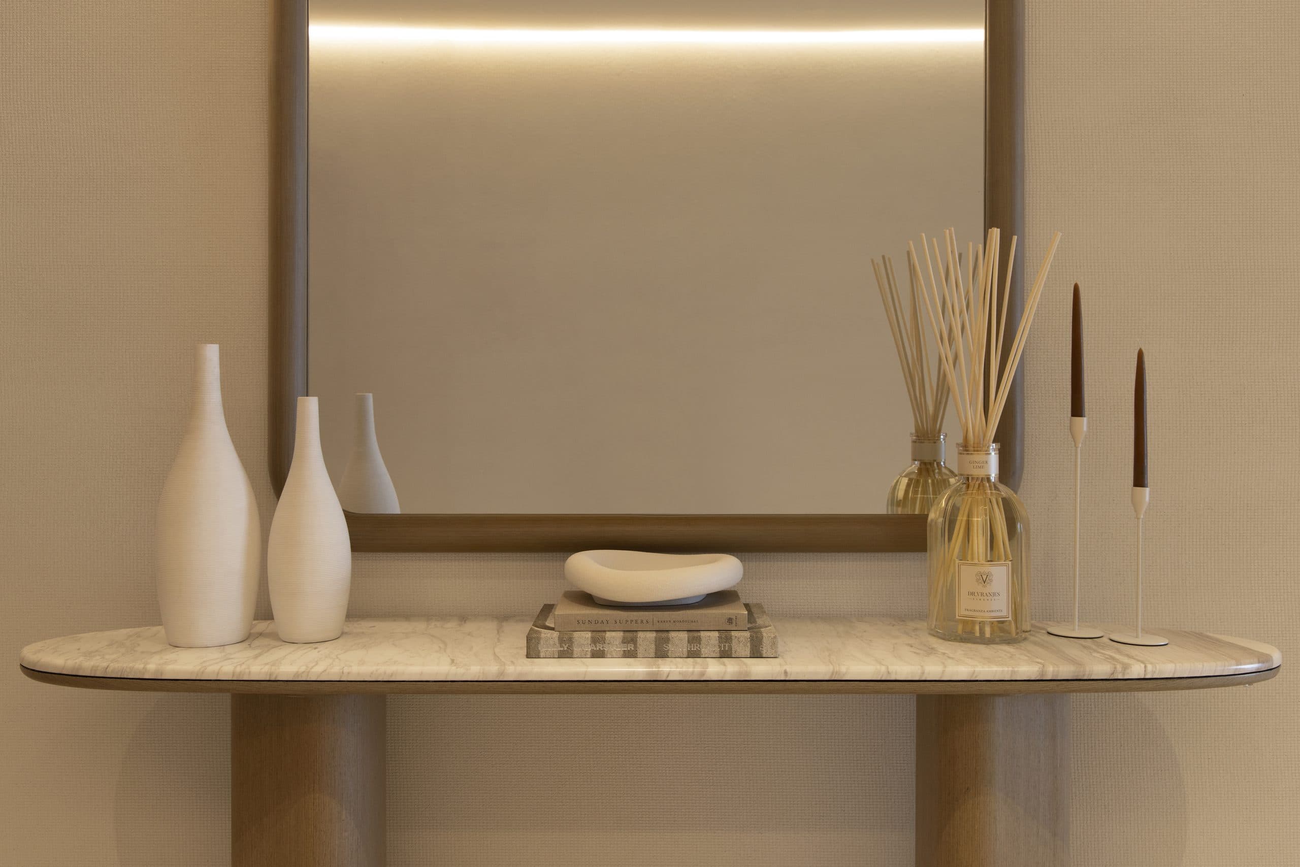 Oak console with a stone top beneath a lit mirror in an oak-panelled hallway